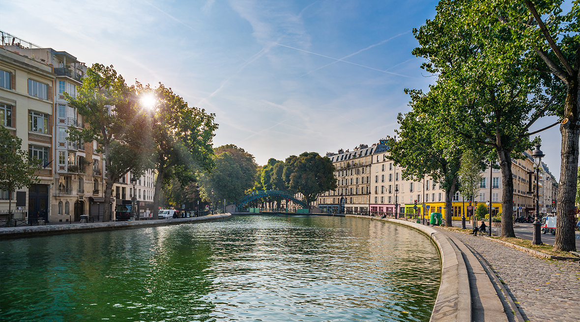canal waters winding through French street with sunshine and leafy trees